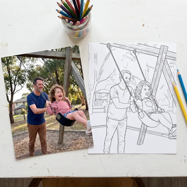 The photo of the dad and daughter on the swing lying on a desk, next to the coloring page drawn from it